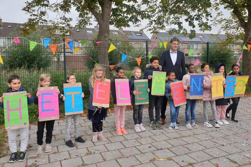 Kinderen vormen met letters de naam van hun school